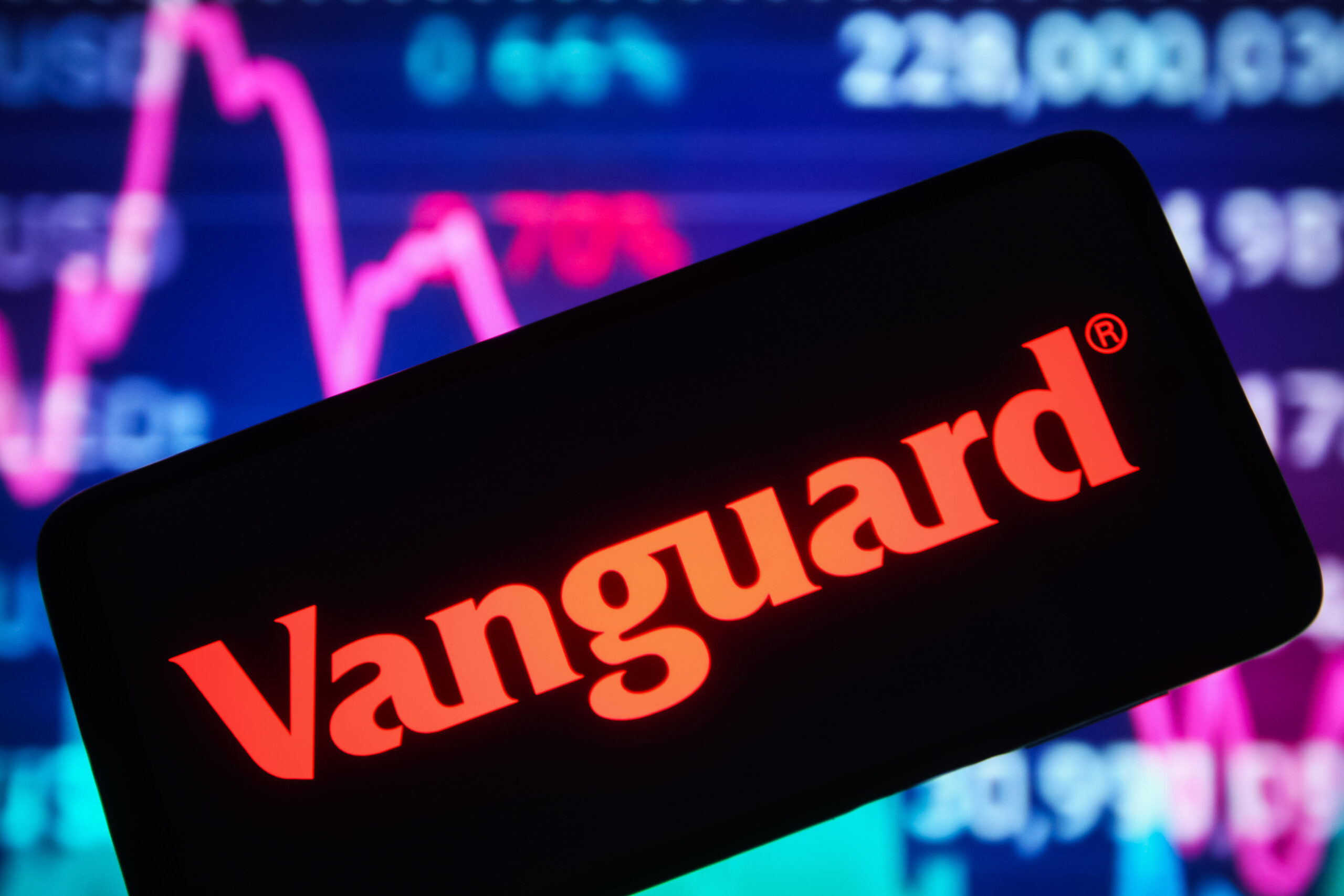 UKRAINE - 2021/12/30: In this photo illustration, the Vanguard Group Inc. logo is seen displayed on a smartphone screen and a stock market line graph is seen in the background. (Photo Illustration by Pavlo Gonchar/SOPA Images/LightRocket via Getty Images)