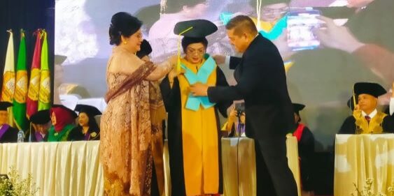 Ketua Yayasan USM Indonesia Dr. Parlindungan Purba SH, MM mengalungkan selempang pengukuhan kepada Prof Ivan Elisabeth Purba. (Foto: Fadmin Malau)