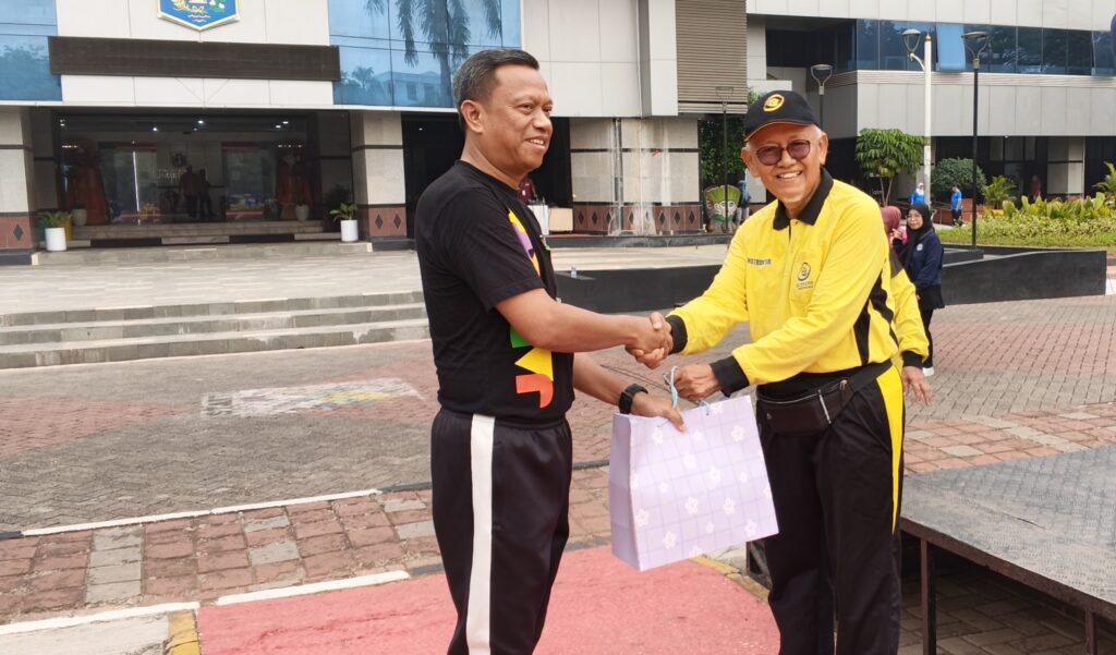 Ketua DPD Ling Tien Kung Jakarta Timur, Ir. H. Mazwar Makmur (kanan), menyerahkan seragam kepada Wali Kota Jakarta Timur, Dr. Munjirin, S.Sos., M.Si. (kiri).