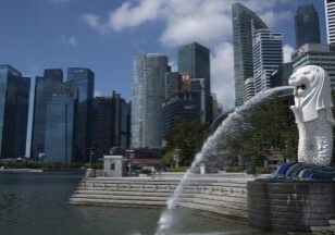 Patung Merlion berdiri di depan gedung-gedung pencakar langit di Singapura,
