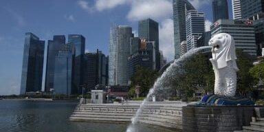 Patung Merlion berdiri di depan gedung-gedung pencakar langit di Singapura,
