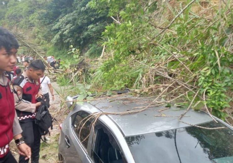 Satu unit mobil sedang melintas tertimbun tanah longsor