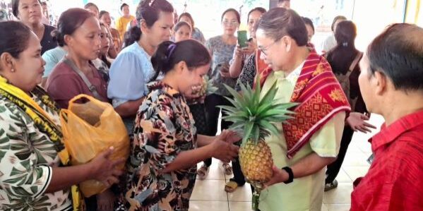 Puluhan ibu-ibu berdiri berbaris sambil menenteng hasil kebun mereka