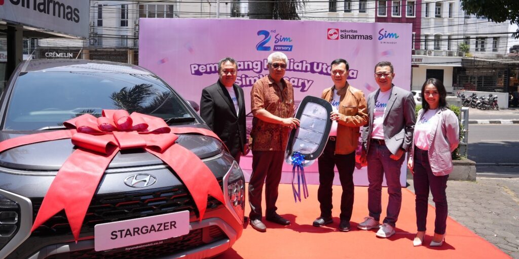 Direktur Utama Sinarmas Sekuritas Jamial Salim (Jaket Coklat) menyerahkan hadiah kepada Hadi Sutandi (Berkemeja Batik) Pemenang Grand Prize Program SimVersary

