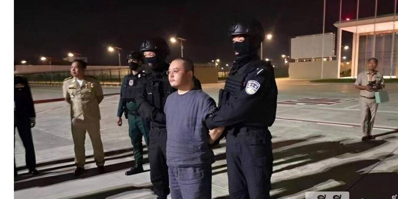 Bos Penipuan Siber,Li Xiong  dengan borgol dikawal oleh polisi China