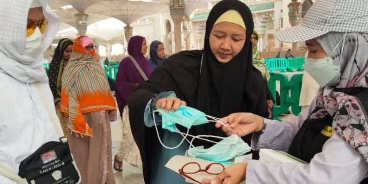 Petugas haji memberikan masker kepada jemaah haji Indonesia. 