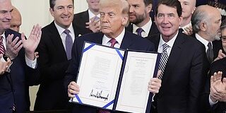 Presiden Trump memegang GENIUS Act yang telah ditandatangani