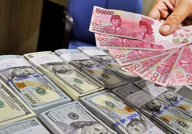 Seorang pegawai tempat penukaran Valutas asing menunjukkan uang rupiah dan uang dolar AS.