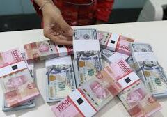 Petugas gerai valuta asing menunjukkan lembaran uang kertas rupiah dan uang dolar AS.