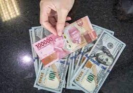 Seorang pegawai gerai penukaran valas sedang memperlihatkan lembaran uang rupiah &amp; dolar AS.
