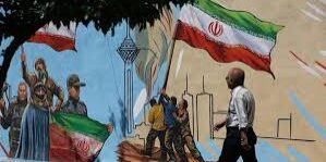 Seorang pria Iran berjalan di samping mural di sebuah jalan di Teheran