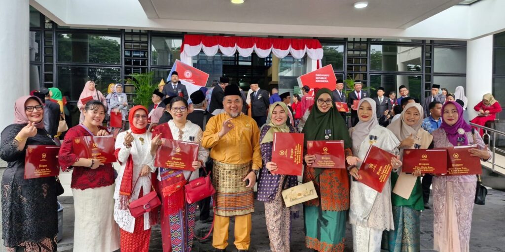 Dekan Fakultas Keperawatan USU, Dr. Dudut Tanjung, M.Kep, Sp.KMB (Warna Kuning Gading) mengenakan pakaian Pasisi berfoto di depan Audiotorium USU Medan

