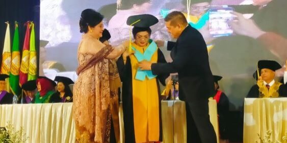 Ketua Yayasan USM Indonesia Dr. Parlindungan Purba SH, MM mengalungkan selempang pengukuhan kepada Prof Ivan Elisabeth Purba. (Foto: Fadmin Malau)