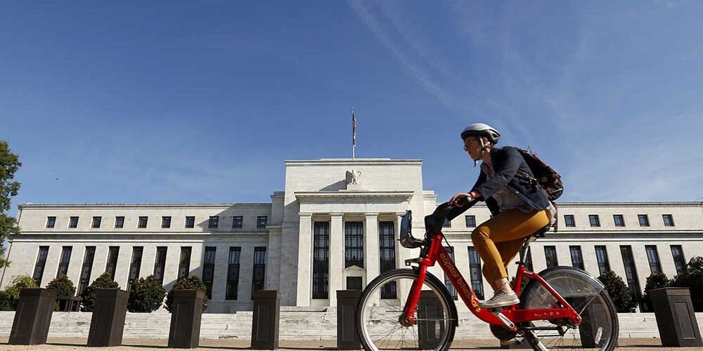 Pesepeda melintasi di depan gedung Federal Reserve di Washington, Amerika Serikat.

